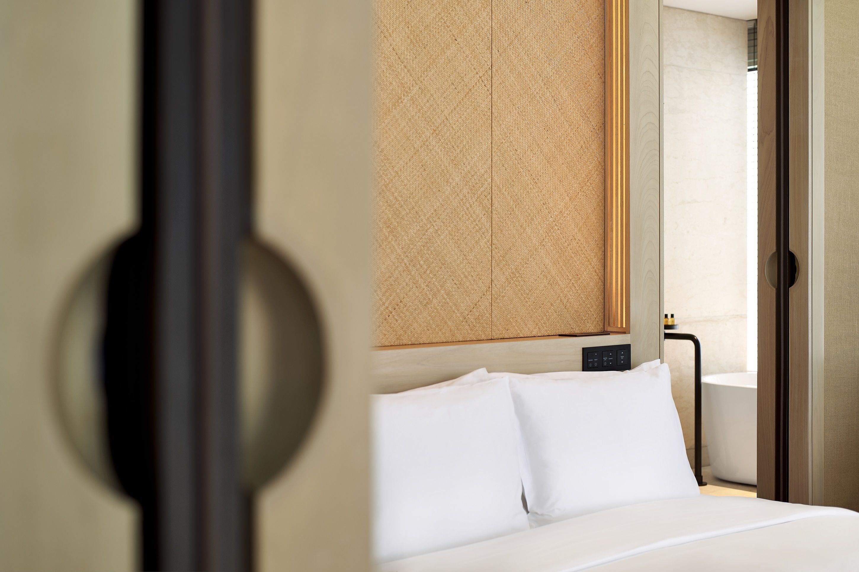 Habitación de hotel con una cama, cabecera de madera y vista al baño.