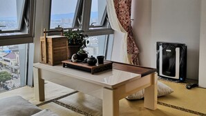 A room with a large window, a table with a tray, a potted plant, and a black speaker. - Emma's home (Suzhou)