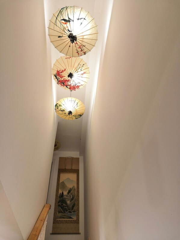 A narrow hallway with three traditional paper umbrellas hanging from the ceiling.