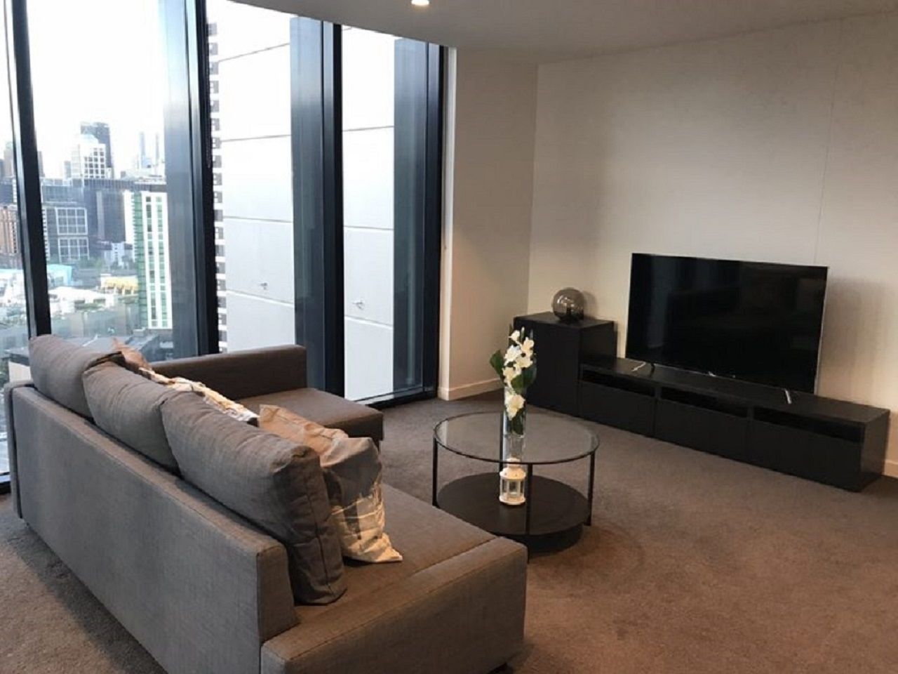 A modern living room with a sofa, a coffee table, and a flat-screen TV.