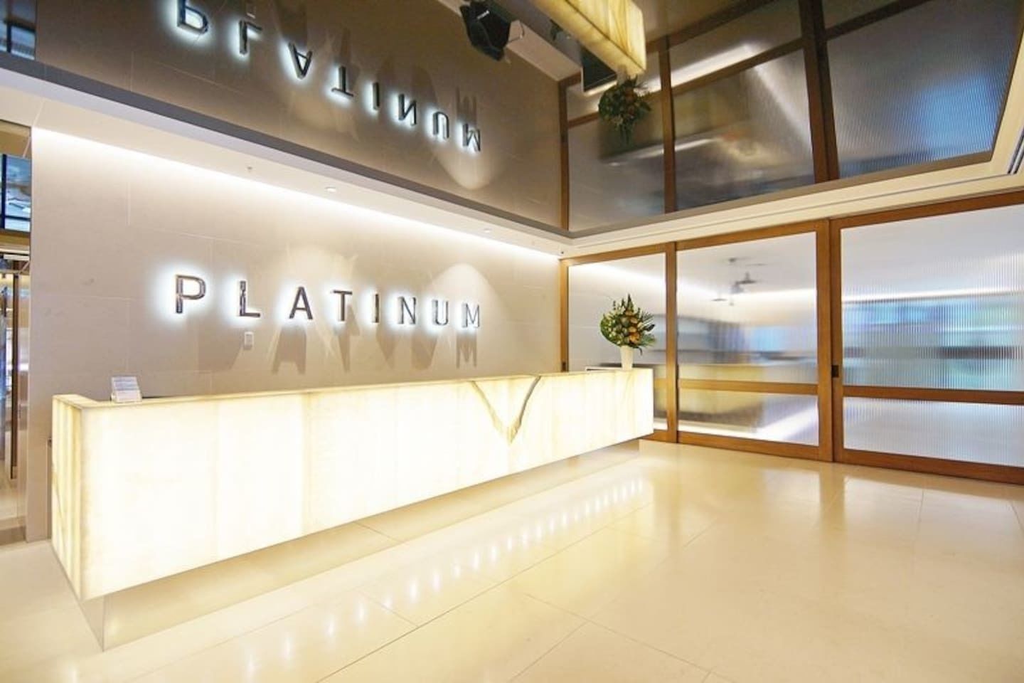 A modern reception area with a 'PLATINUM' sign, a reception desk, and a large window with a view.