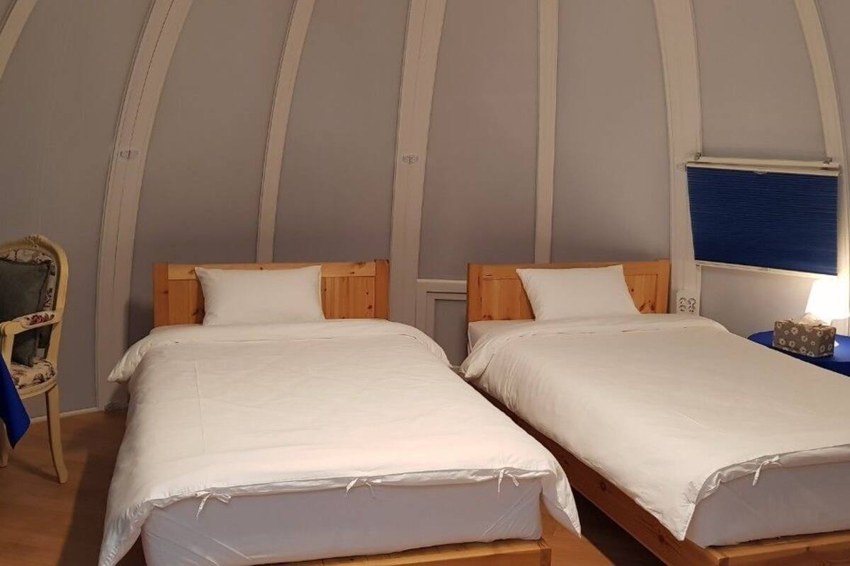 Een kamer met twee bedden, een stoel, een tafel en een lamp.