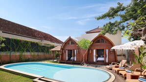 A swimming pool with lounge chairs and a wooden deck. - Kubu GWK Villa (Jimbaran)