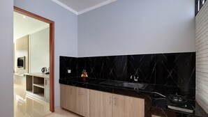 A modern kitchen with black marble backsplash, wooden cabinets, and a stainless steel sink. - Kubu GWK Villa (Jimbaran)