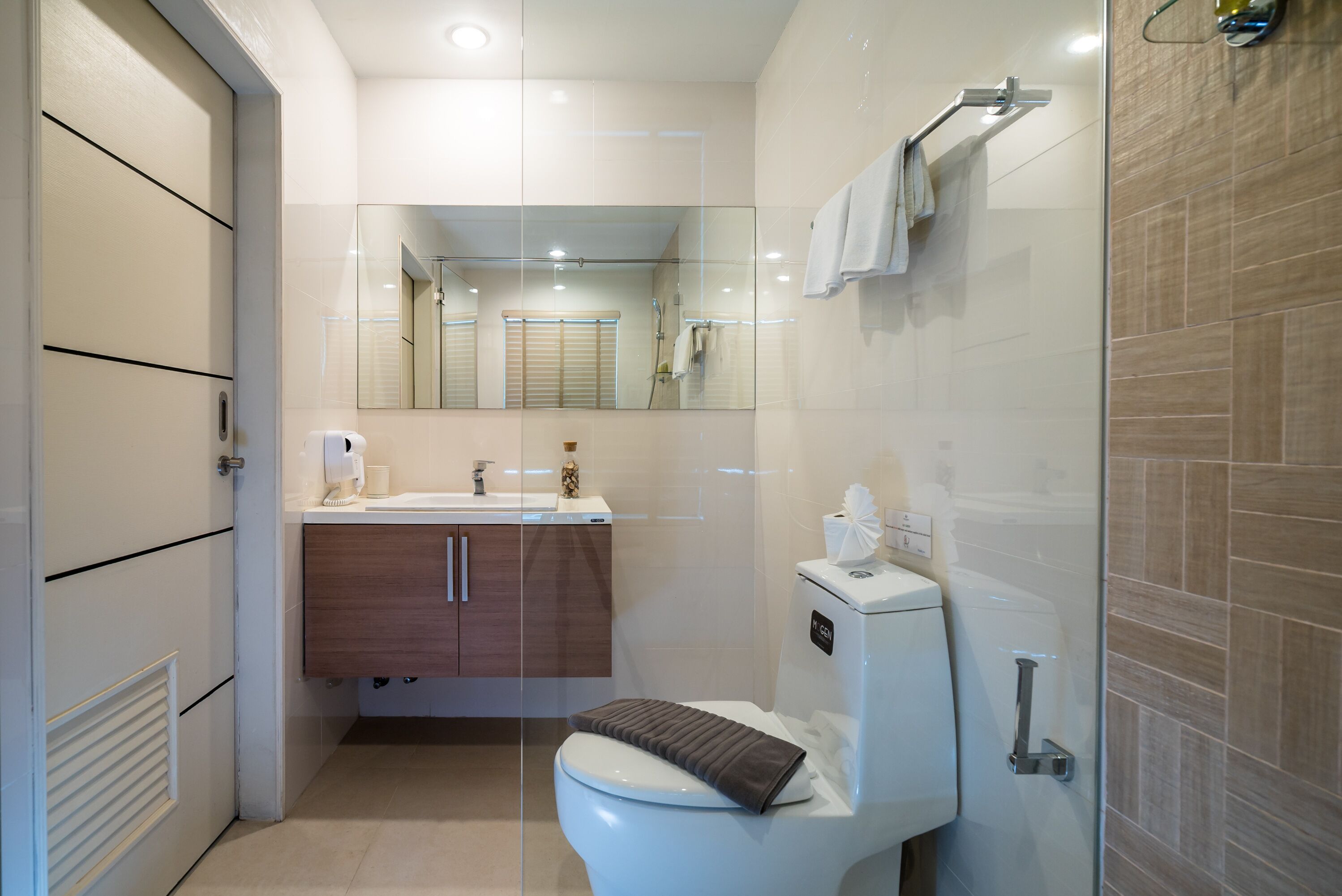 Un baño moderno con inodoro, lavamanos, espejo y zona de ducha.