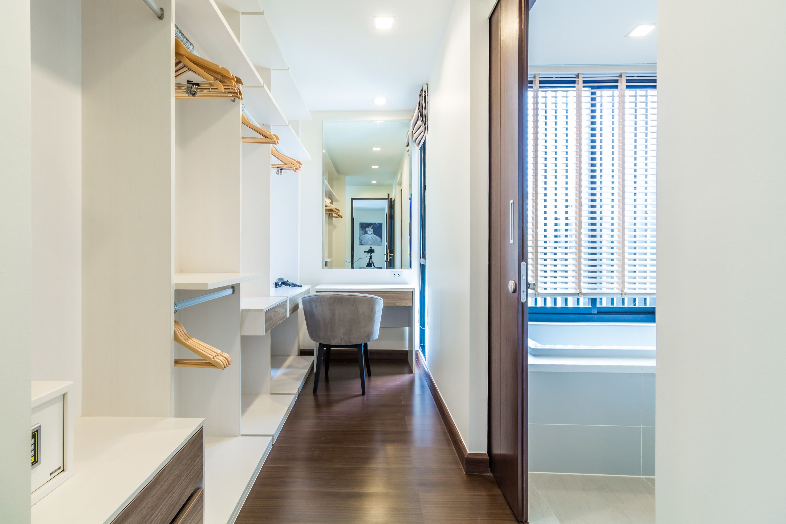 A modern bathroom with a wooden vanity, a chair, and a large mirror.
