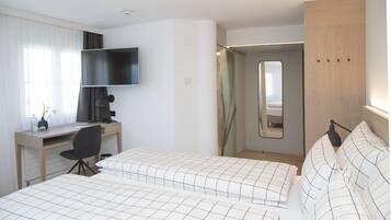 Habitación de hotel con dos camas, un escritorio, una silla, un televisor y un espejo.