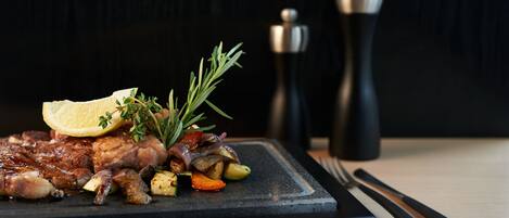 A plate of food with a lemon wedge, rosemary, and a pepper grinder in the background.