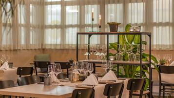 A restaurant with tables set for dining, candles, and potted plants.