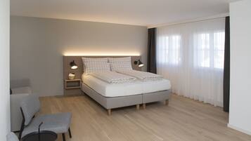 Un dormitorio moderno con una cama, lámparas de noche, una silla y una mesita.
