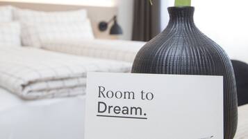 A room with a bed, a vase with a flower, and a sign that reads "Room to Dream."