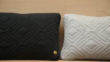 Dos almohadas con diseño de rombos, una negra y otra blanca, sobre una superficie de madera.