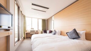 Une chambre d’hôtel avec un grand lit, un bureau, une chaise et un téléviseur.