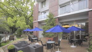 Un espace extérieur aménagé en terrasse, avec des sièges, des parasols et des plantes en pot.