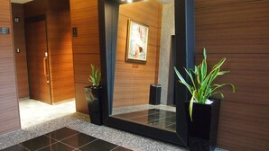 Un hall d’entrée moderne agrémenté d’un grand miroir, de lambris en bois et de deux plantes en pot.