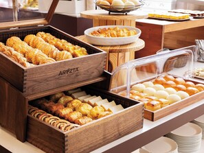 A buffet with various baked goods including pastries and bread.