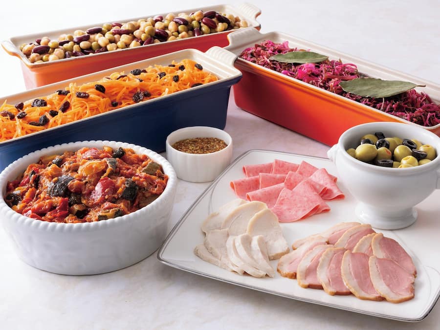 A variety of food items including vegetables, olives, and sliced meats arranged on a table.