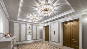 A spacious hallway with a patterned carpet, elegant chandeliers, and a set of double doors. - Takarazuka Hotel (Takarazuka)