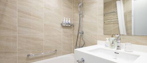 A modern bathroom with a bathtub, a shower, and a sink. There are handrails and a mirror above the sink.