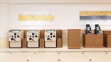 A reception area with self-service kiosks, wooden cabinets, and two abstract paintings on the walls.