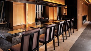 A modern dining area with a long table, multiple chairs, and a kitchen in the background. - Takarazuka Hotel (Takarazuka)