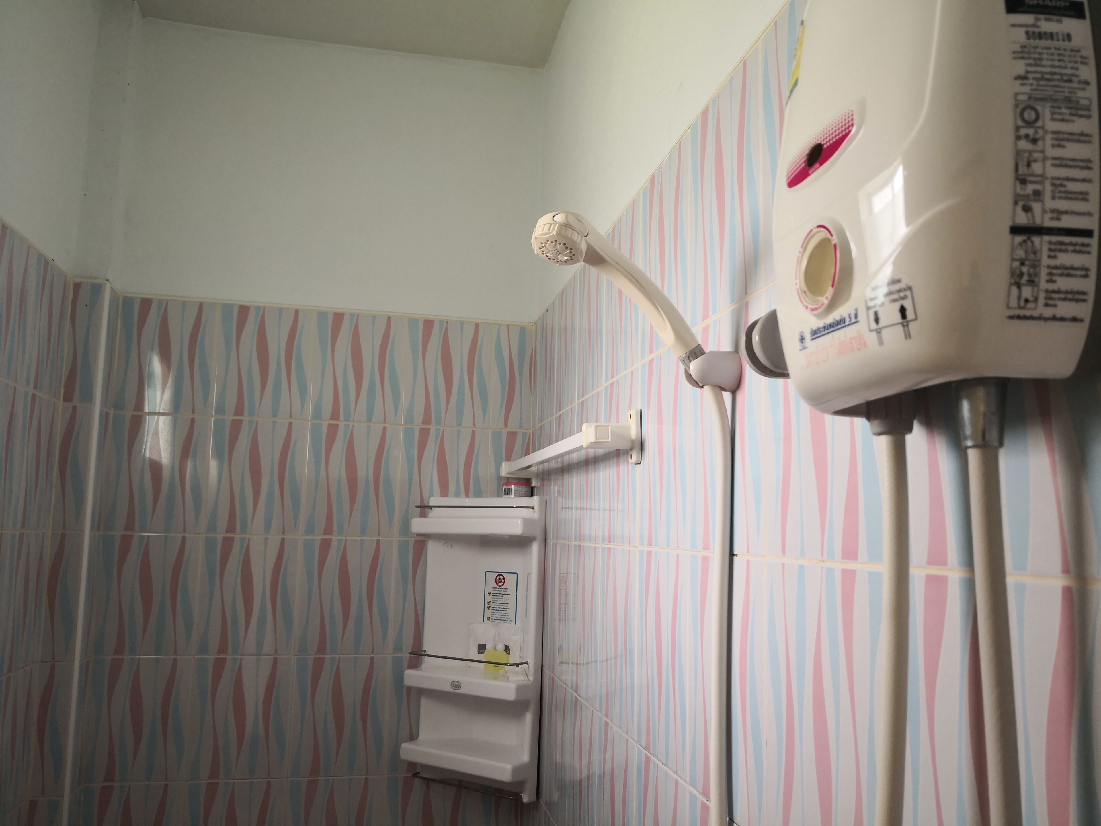 Ein Badezimmer mit Dusche, Handtuchhalter und Durchlauferhitzer.