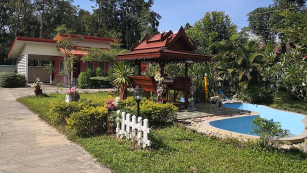 Un jardín con un pabellón, una piscina y un edificio de techo rojo.