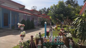 Un jardín con una cerca decorativa, plantas en macetas y un cartel.
