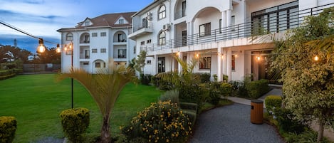 A multi-story hotel with a well-maintained lawn and garden area.