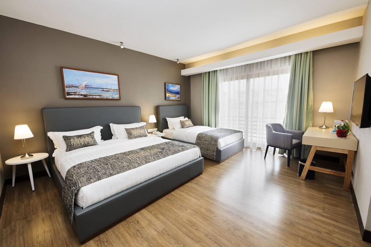 Habitación de hotel con dos camas, un escritorio y una silla.