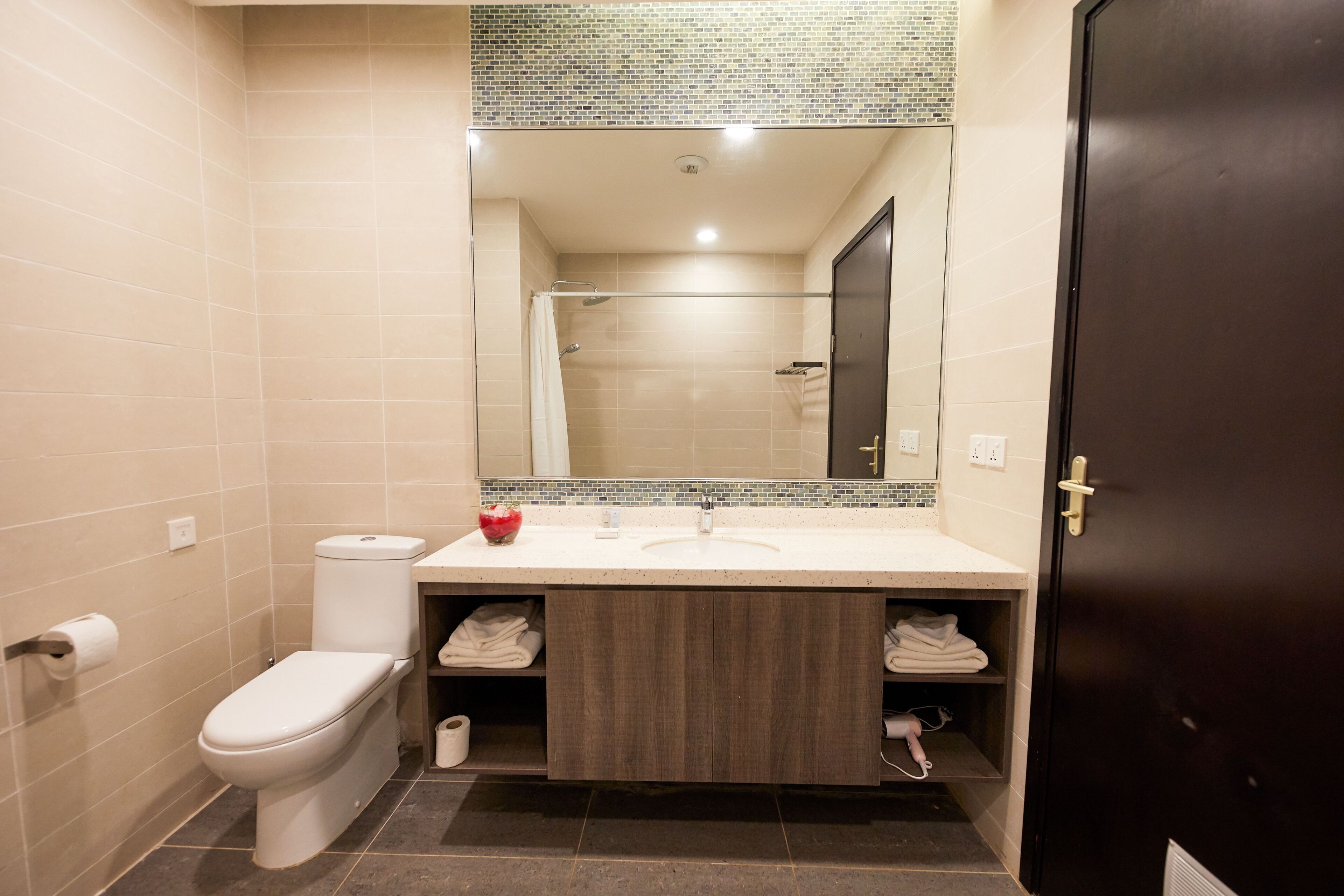 A modern bathroom with a toilet, sink, and mirror.