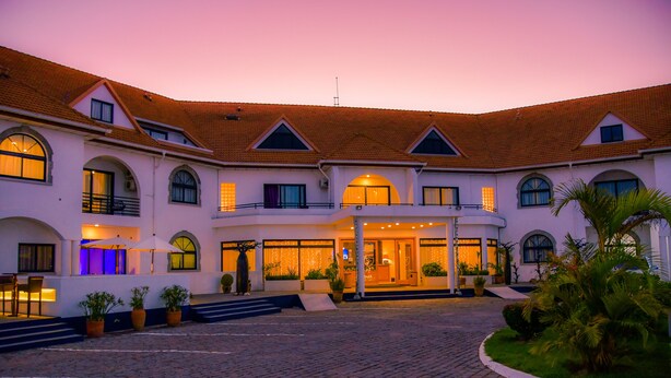A large, multi-story building with a central entrance, arched windows, and a tiled roof.
