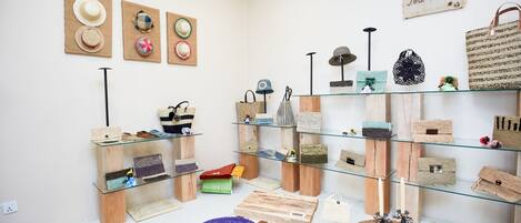 Una habitación con cestas y sombreros tejidos exhibidos en estantes y mesas.