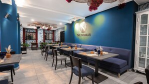 A restaurant interior with blue walls, a logo on the wall, and a seating area with tables and chairs.