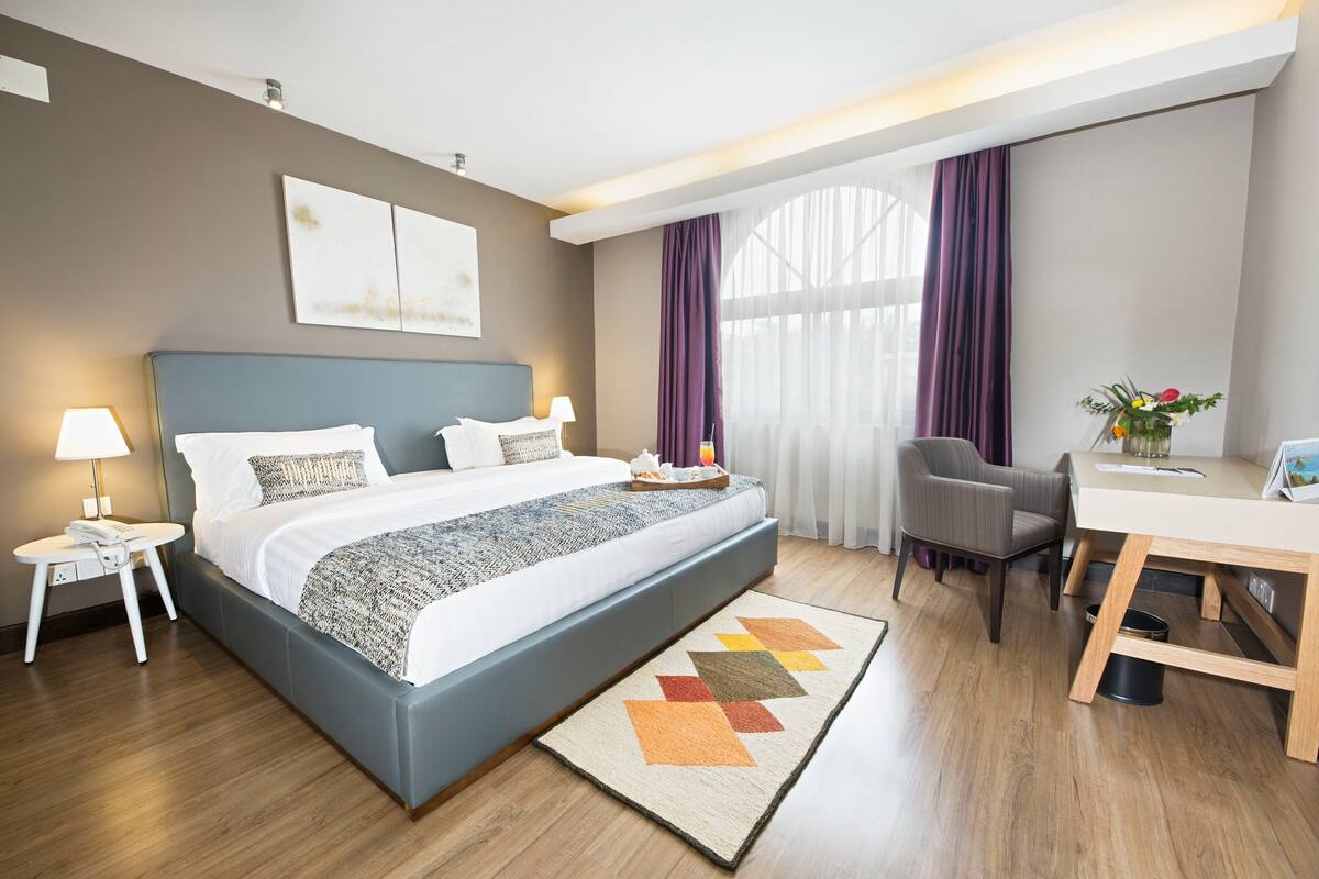 Una habitación de hotel moderna con una cama grande, un escritorio y una silla.