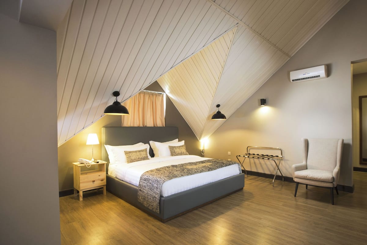 Un dormitorio moderno con una cama grande, mesitas de noche, una silla y una lámpara colgante.