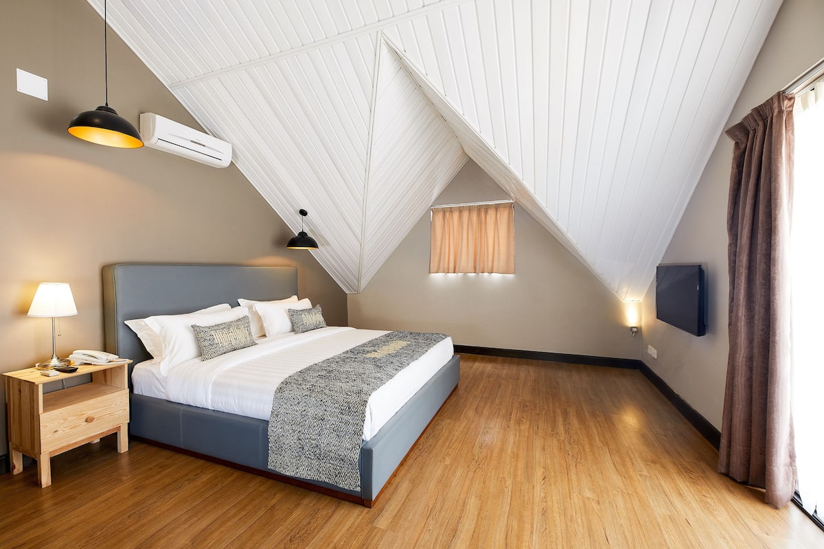 Un dormitorio con cama, mesita de noche, lámpara, aire acondicionado y televisor montado en la pared.