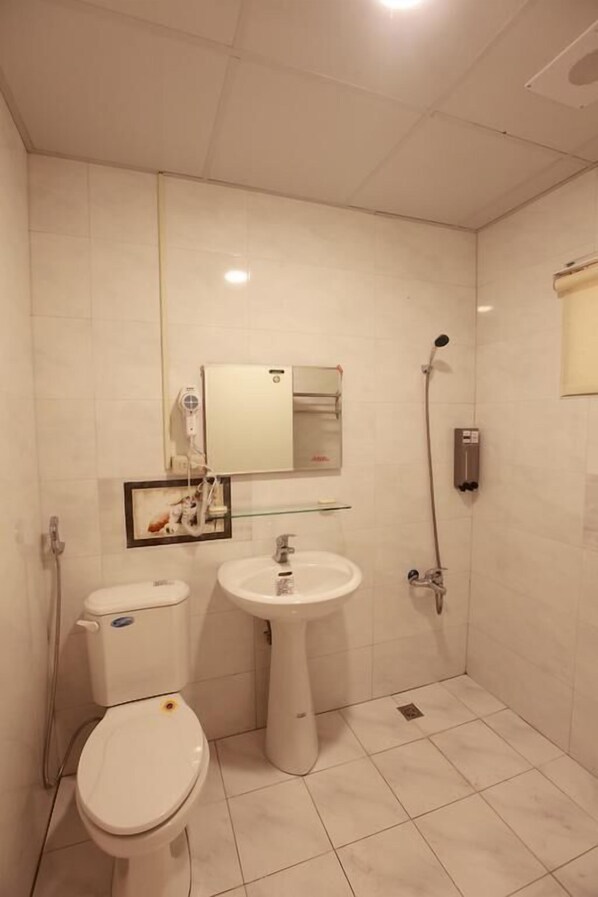 A small, clean bathroom with a toilet, sink, and shower.
