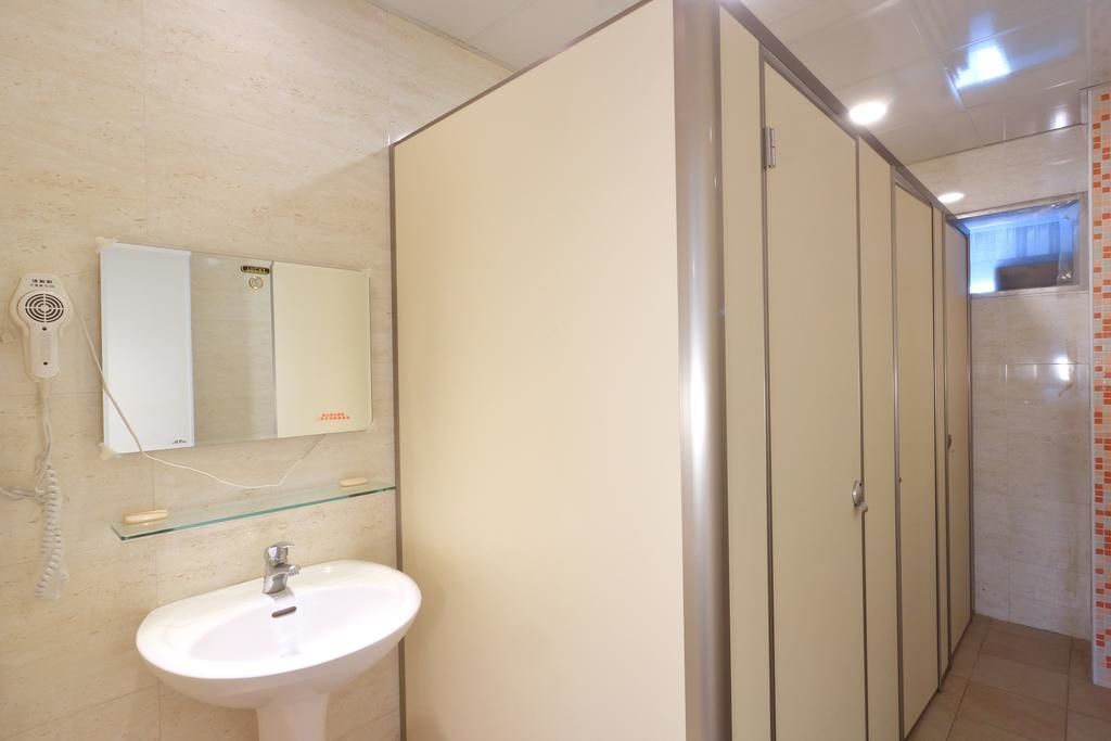 A bathroom with a white sink, a mirror, and a glass shelf.