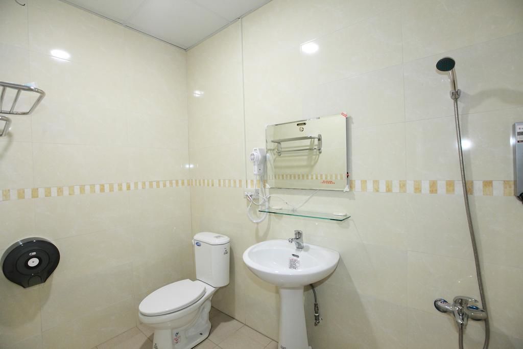 A small bathroom with a toilet, sink, and shower.