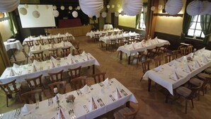 A banquet hall with multiple round tables set for dining, wooden chairs, and white tablecloths. - Landgasthof Voltmer (Burgdorf)