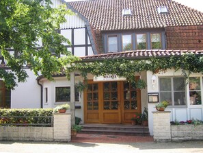 Un bâtiment traditionnel avec un toit en tuiles, une porte d’entrée en bois et une enseigne portant l’inscription « VOLTMER ».