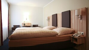 A hotel room with two beds, a desk, a chair, a lamp, and a phone on a bedside table. - Landgasthof Voltmer (Burgdorf)