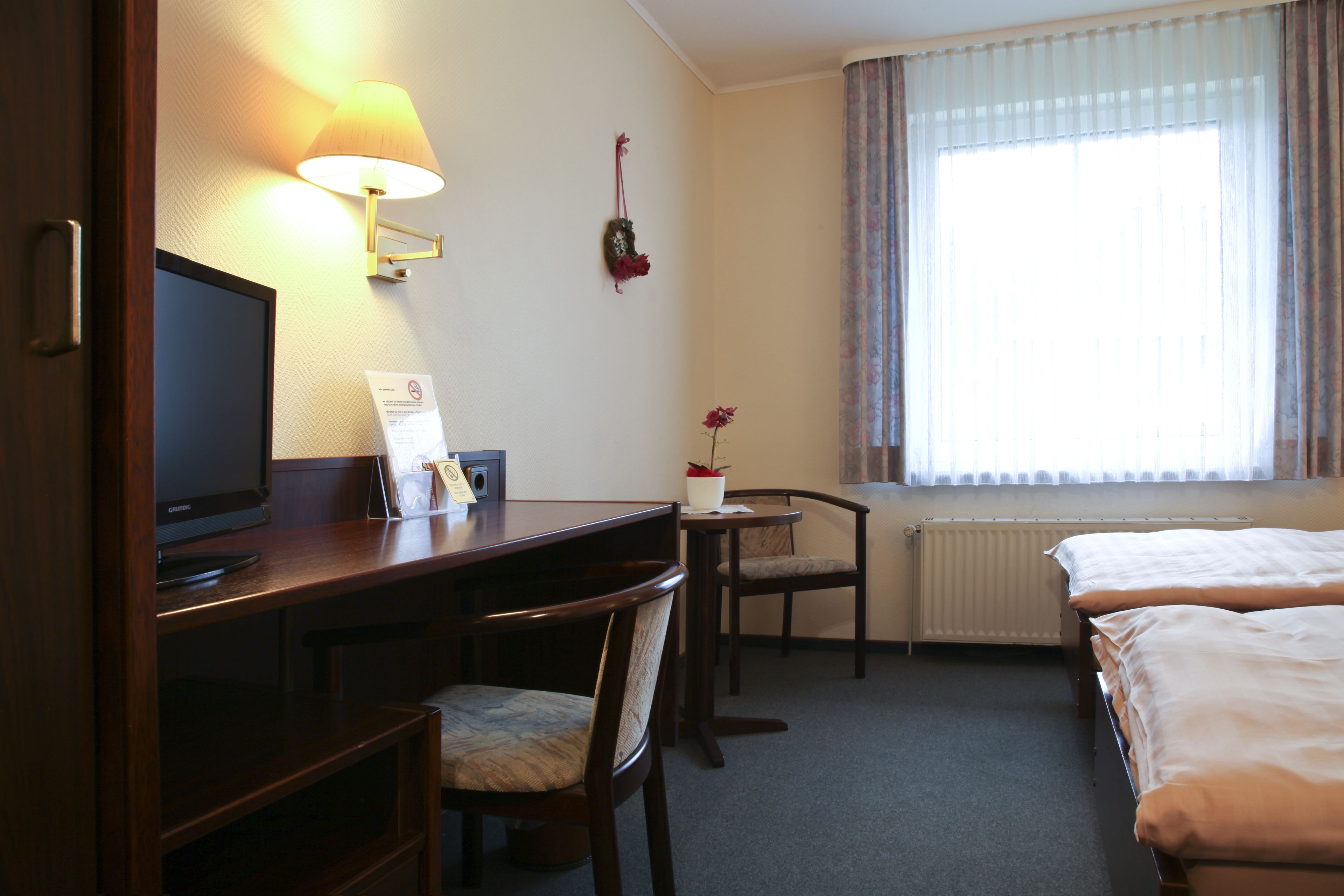 Habitación de hotel con escritorio, silla, televisor y dos camas.
