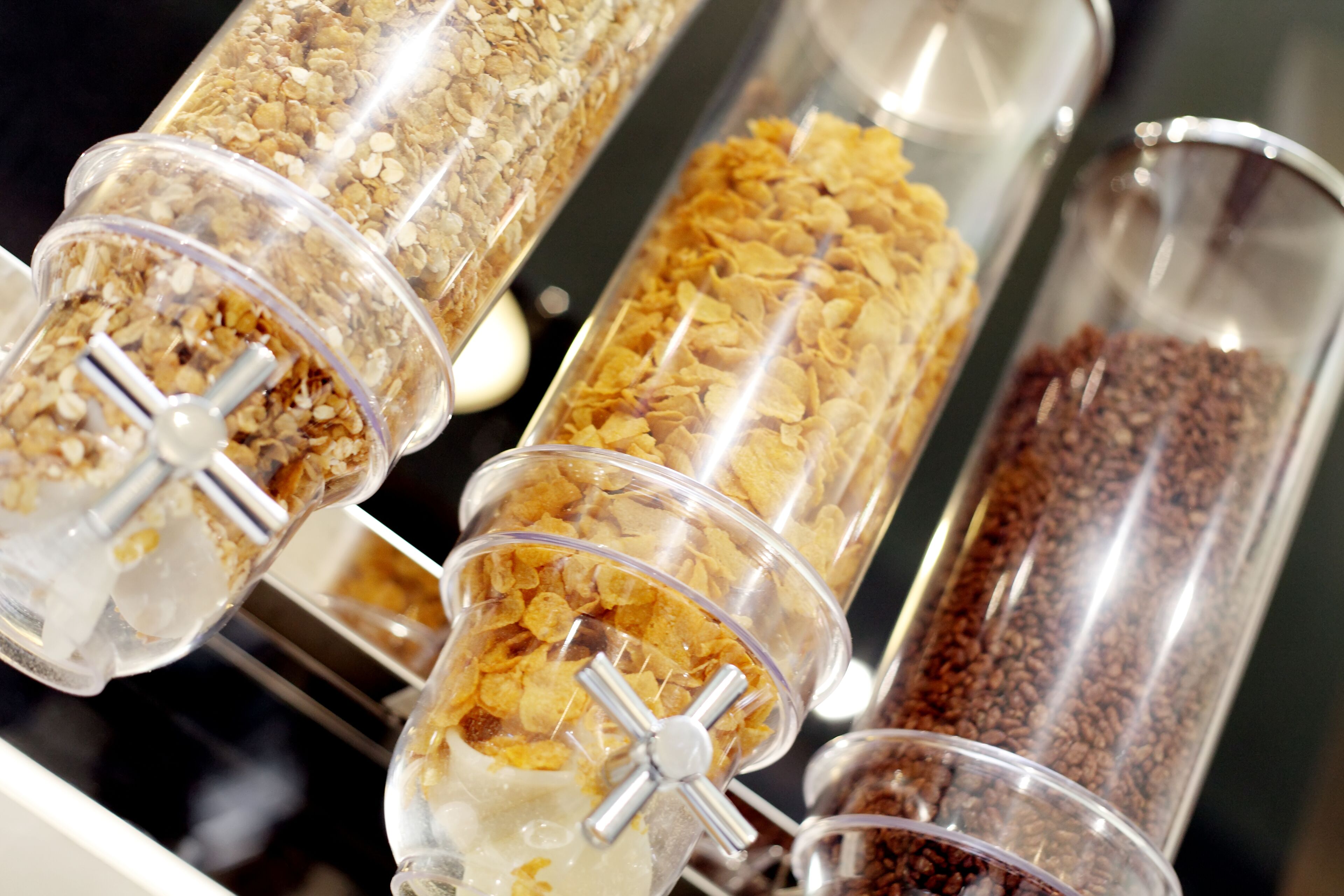 A food display with various types of cereal in transparent containers.