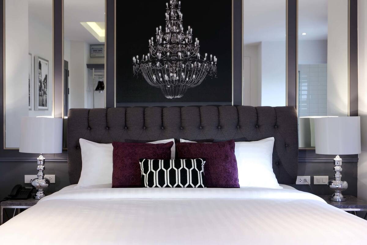 A hotel room with a large bed, a chandelier, and a modern design.