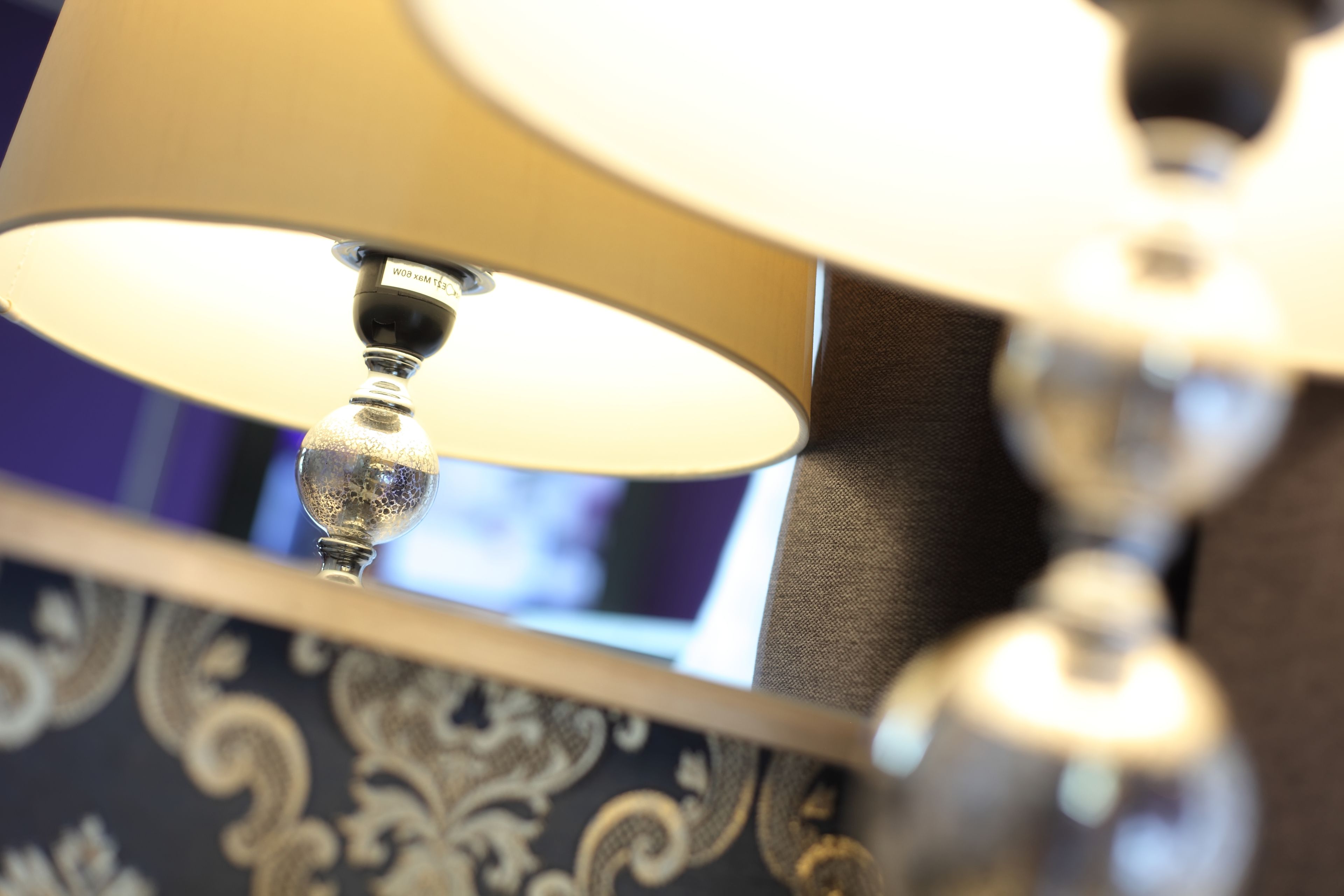 Een detail van een lamp met een metalen voet en een stoffen kap.