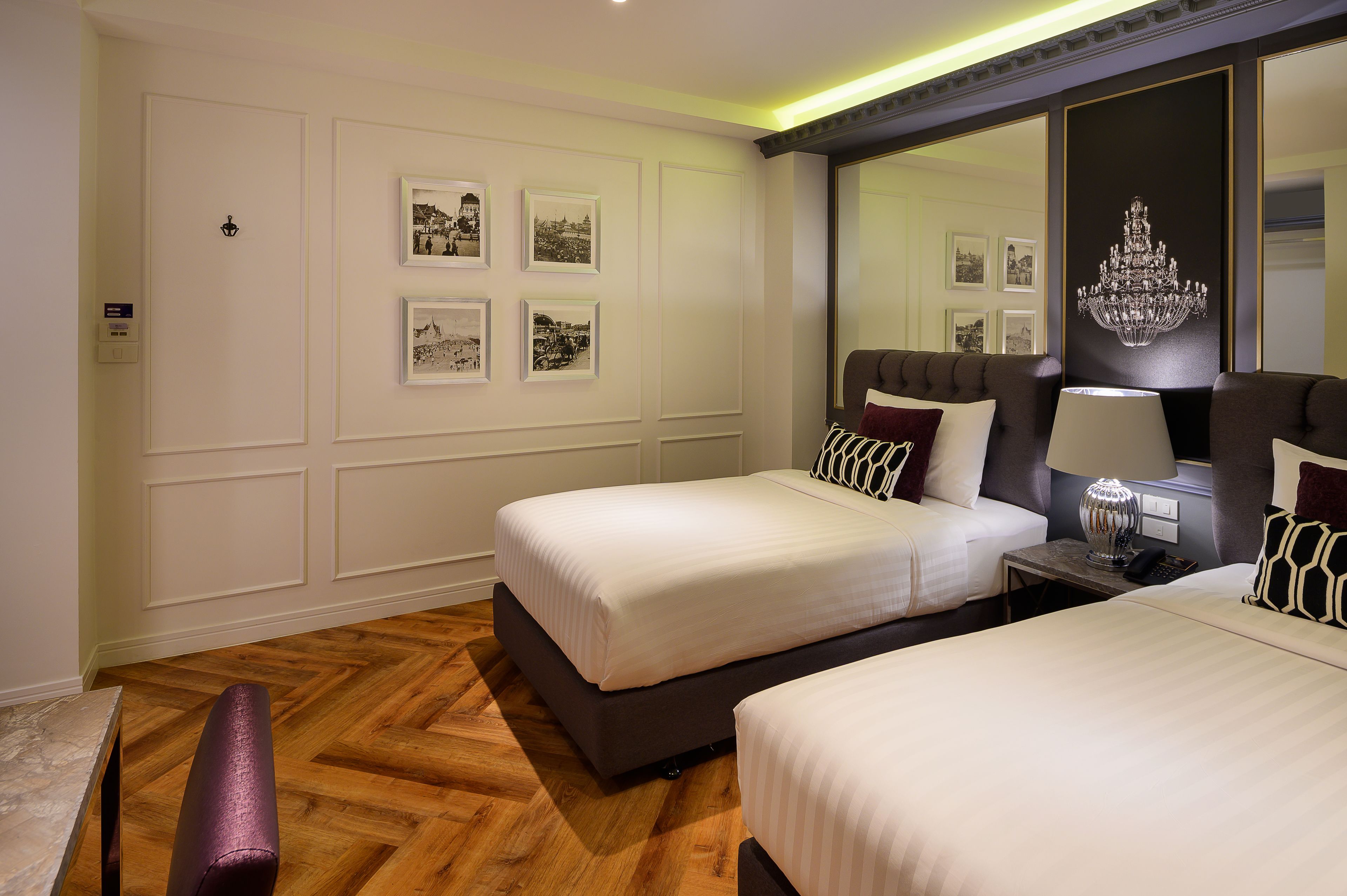 A hotel room with two beds, a large mirror, and framed pictures on the wall.