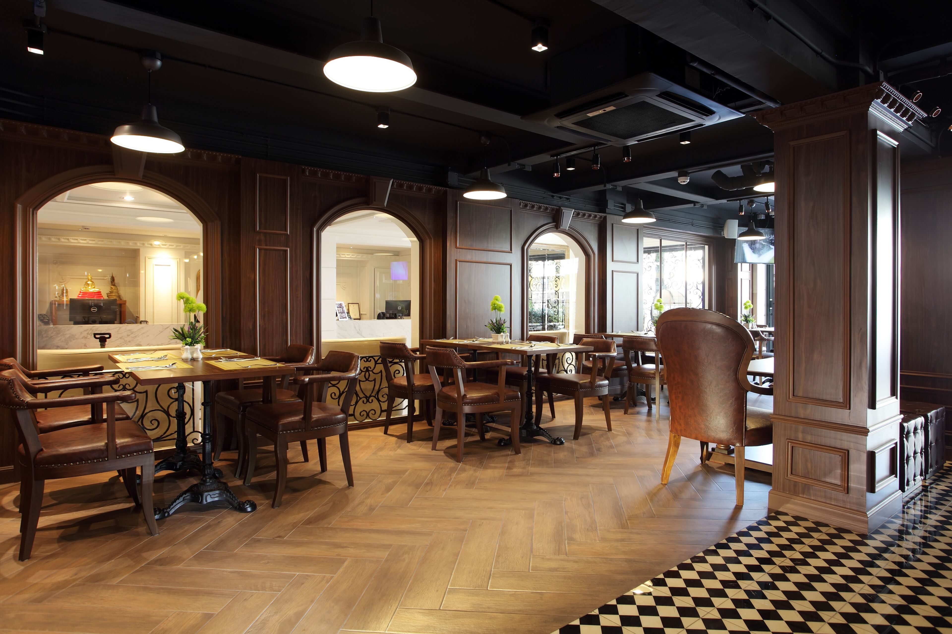 A restaurant with wooden furniture, black and white checkered flooring, and large windows.