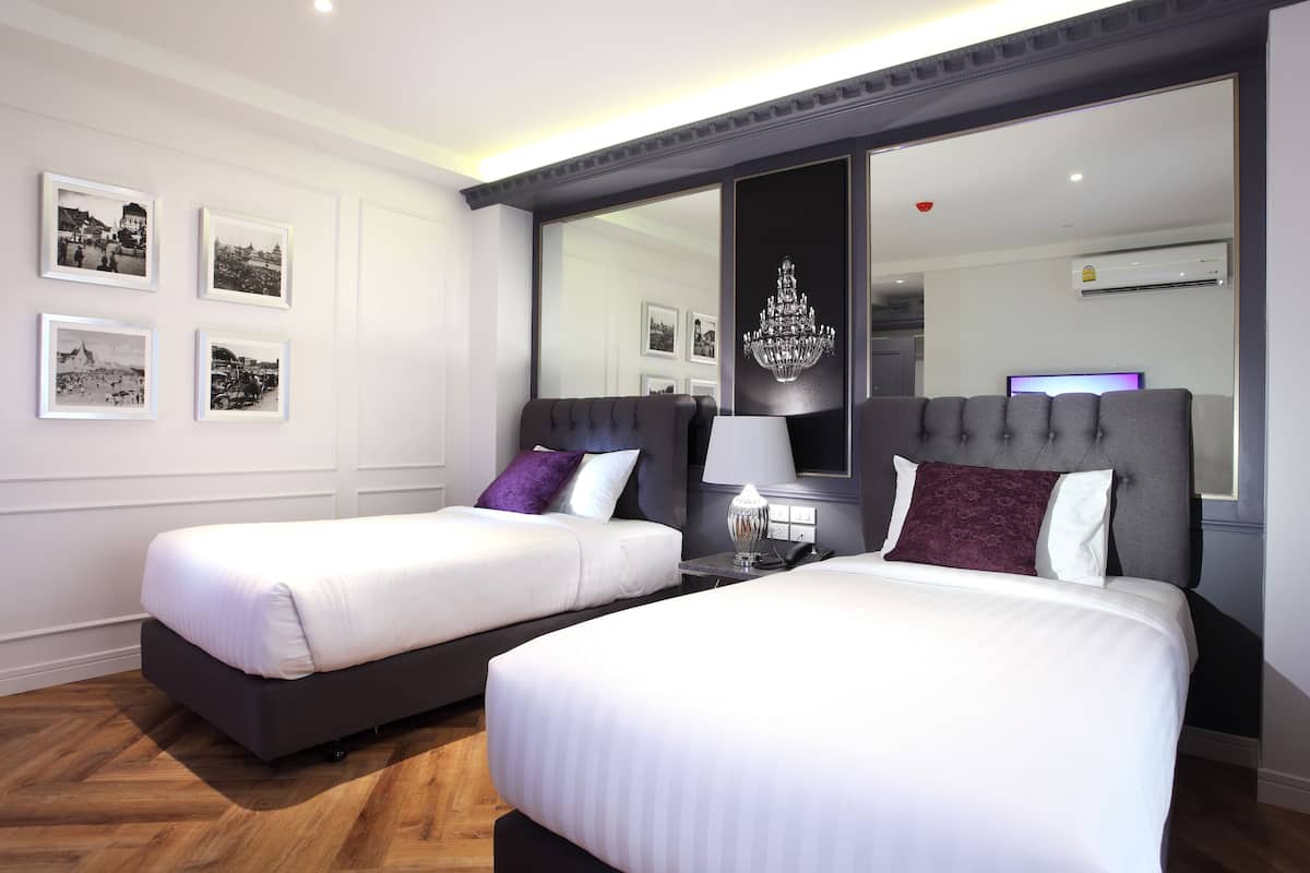 A hotel room with two beds, a large mirror, and framed pictures on the wall.